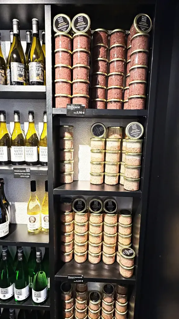Regal mit Wein und Feinkostgläsern in der Stadtmetzgerei
